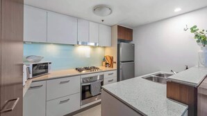 Une cuisine moderne avec des armoires blanches, des appareils en acier inoxydable et un comptoir en granit.