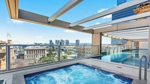 Une piscine sur le toit offrant une vue sur la ville, une balustrade en verre et une conception architecturale moderne.