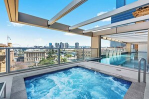 Ein Pool auf dem Dach mit Blick auf die Stadt, einer Glasbrüstung und einem modernen architektonischen Design.