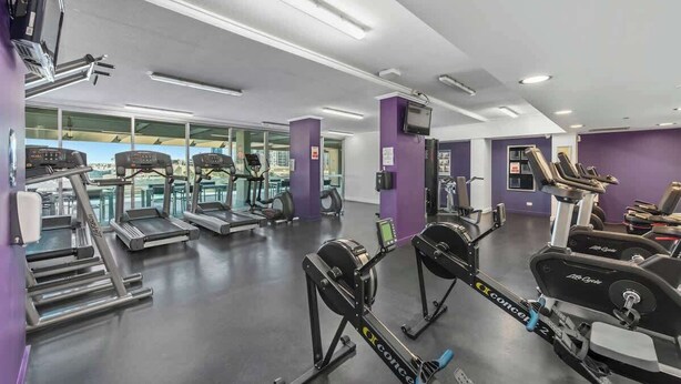 Une salle de sport équipée de tapis de course, de vélos elliptiques et de matériel de musculation.