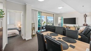 Un salon moderne comprenant un coin repas, un téléviseur et une guitare.