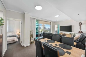 Ein modernes Wohnzimmer mit Essbereich, einem Fernseher und einer Gitarre.