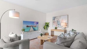 A modern living room with a sofa, a coffee table, a TV, and artwork on the wall. - City Escape! 2bed-2bath-1car-pool-views - CBD (Brisbane)