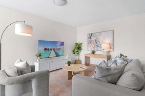 Ein modernes Wohnzimmer mit einer Couch, einem Couchtisch, einem Fernseher und Bildern an der Wand.