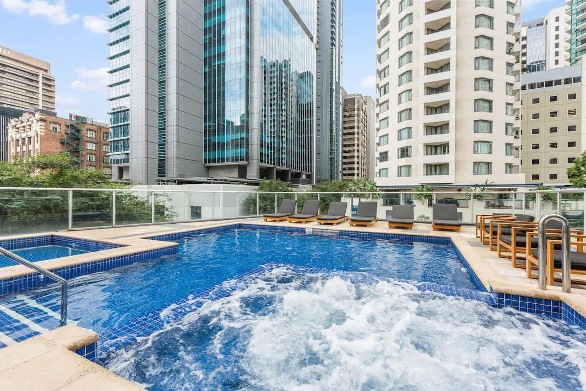 Une piscine sur le toit, dotée d’un jacuzzi, entourée d’immeubles modernes.