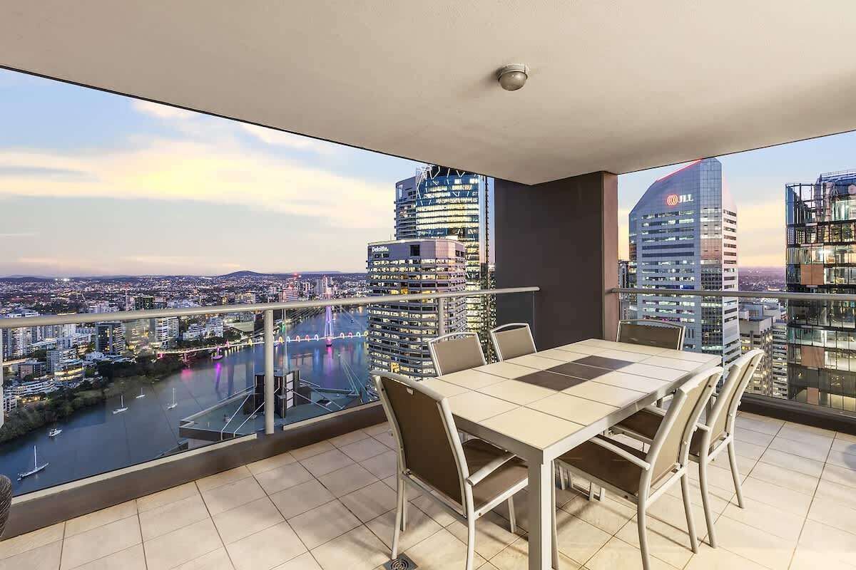 Ein Balkon mit Blick auf die Stadt, einem Tisch mit Stühlen und einem Geländer.