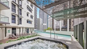 A rooftop pool area with a hot tub, lounge chairs, and a view of surrounding buildings. - Amazing! 2bed/2bath/1car/balcony/views ~ CBD (Brisbane)