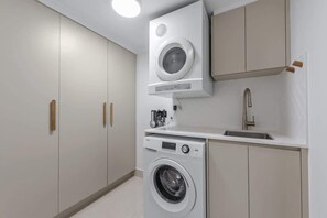 A compact laundry room with a washing machine, a dryer, and a sink. - Skyline Stunner! 3bed/2bath/1car/views ~ CBD (Brisbane)