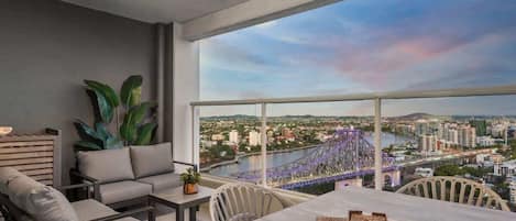 A balcony with a city view, a sofa, a table, and a chair.