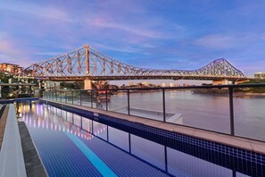 Piscina com vista para uma ponte e paisagem urbana.