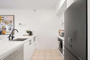 Eine moderne Küche mit weißen Schränken, einem schwarzen Kühlschrank und einer Mikrowelle.