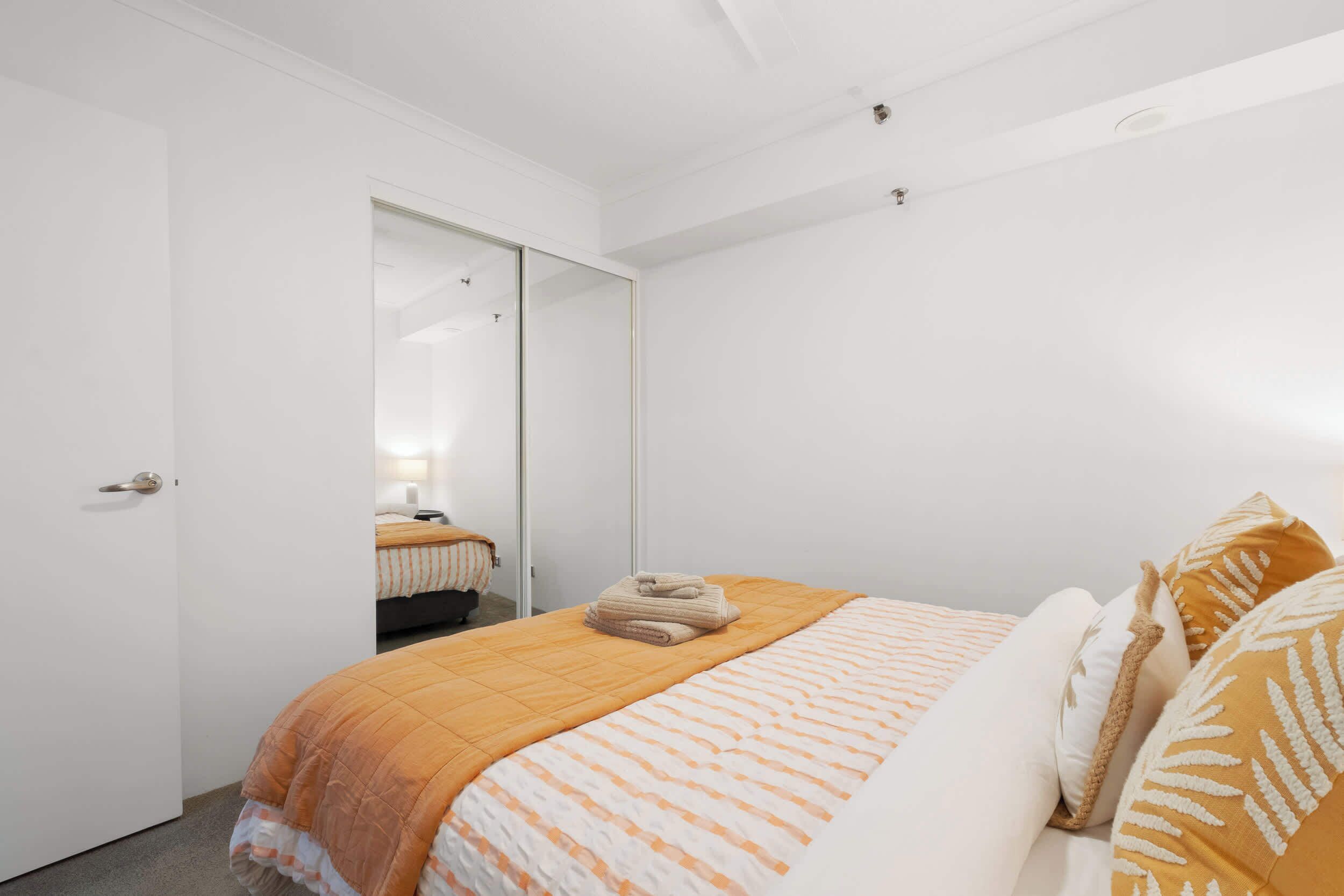 A bedroom with a bed, a wardrobe, and a mirror.