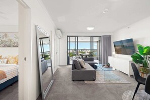 Sala de estar moderna com sofá, mesa de jantar e uma grande janela com vista para a cidade.