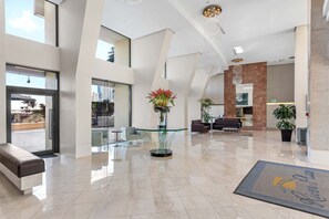 Um hall amplo com uma mesa de centro de vidro, área de estar e balcão de recepção.
