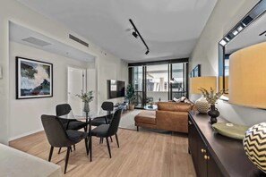 A modern living room with a sofa, dining table, chairs, and a TV. - South Bank Sensational! ~ 1bed,1bath,1car,balcony (Brisbane)