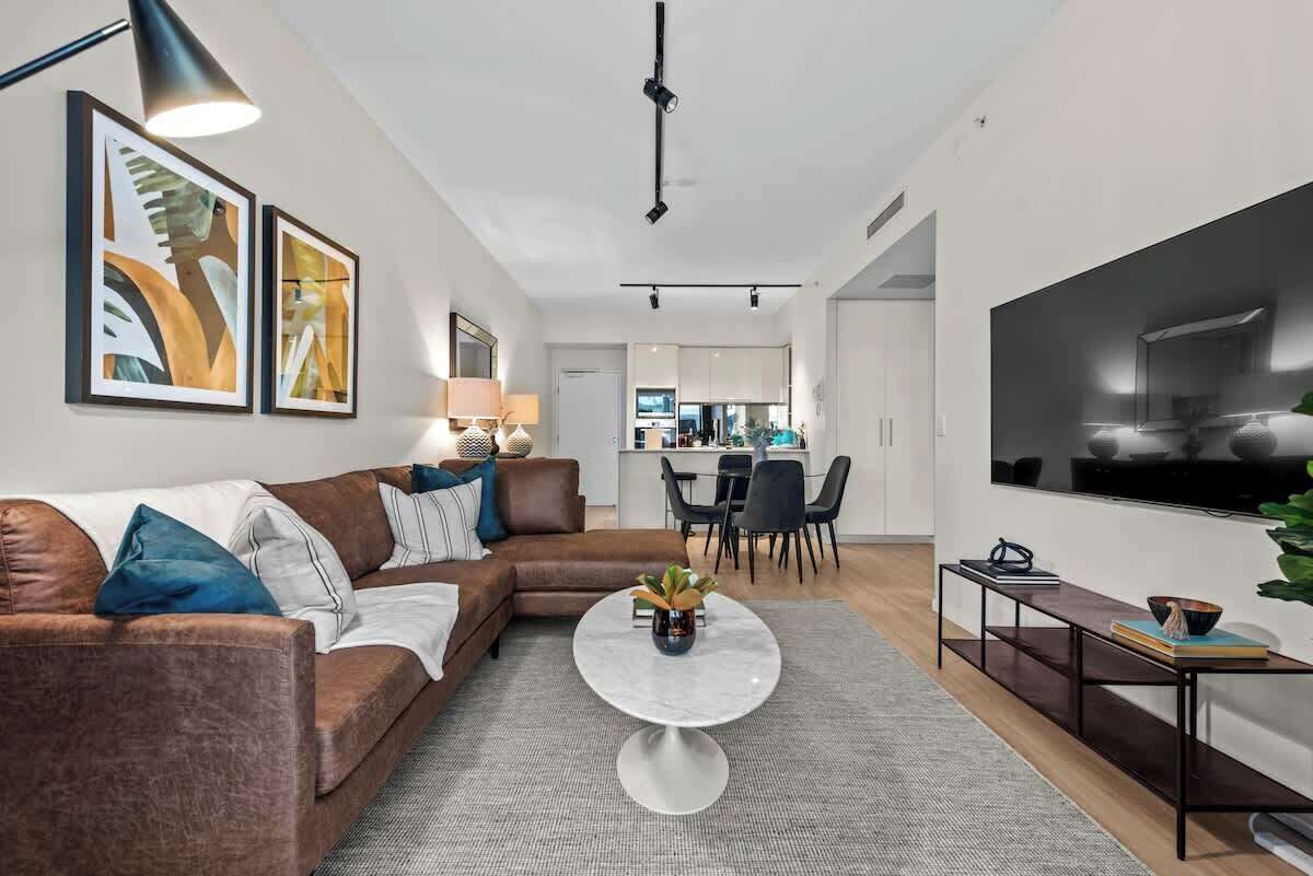 A modern living room with a sectional sofa, a round coffee table, and a flat-screen TV.