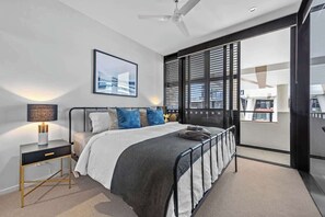 A modern bedroom with a bed, bedside table, lamp, and a large window with blinds. - South Bank Sensational! ~ 1bed,1bath,1car,balcony (Brisbane)