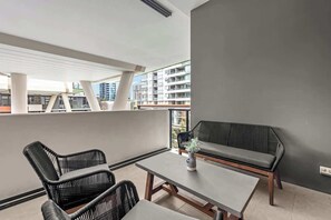 Ein Balkon mit einer Couch, zwei Stühlen und einem Tisch.