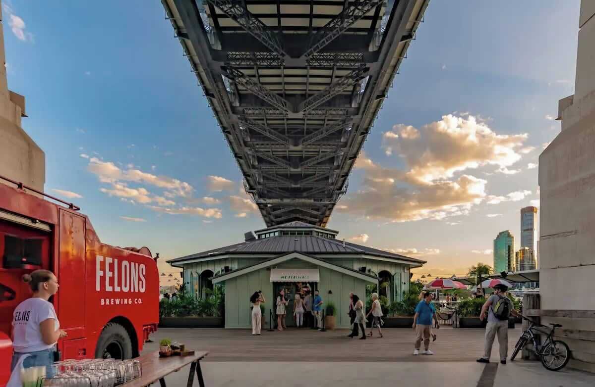 A building with a unique architectural design, a red truck labeled 'FELONS BREWING CO.', and people walking around.