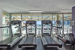 A gym with treadmills, exercise bikes, and a rowing machine, with large windows offering a city view. - City Heights! 2bed/1bath/1car/views ~ CBD (Brisbane)