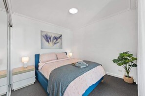 A bedroom with a bed, bedside tables, a wall-mounted artwork, and a potted plant. - City Heights! 2bed/1bath/1car/views ~ CBD (Brisbane)