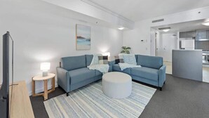 A modern living room with a sofa set, a round ottoman, a small side table with a lamp, and a painting on the wall. - City Heights! 2bed/1bath/1car/views ~ CBD (Brisbane)