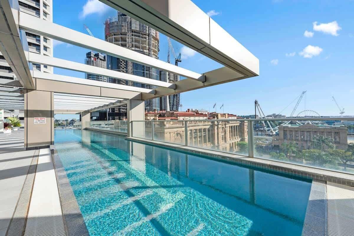 A rooftop pool with clear blue water, modern architecture, and a view of the city skyline.