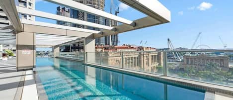 A rooftop pool with clear blue water, modern architecture, and a view of the city skyline.