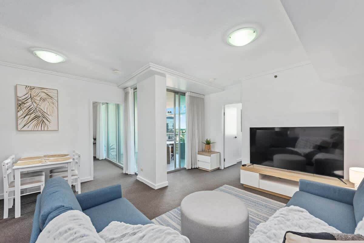 A modern living room with a sofa, TV, and a dining area with chairs and a table.