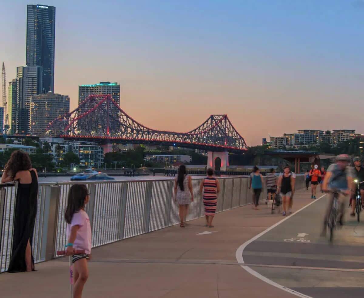 A pedestrian bridge with a view of a bridge and buildings in the background.
