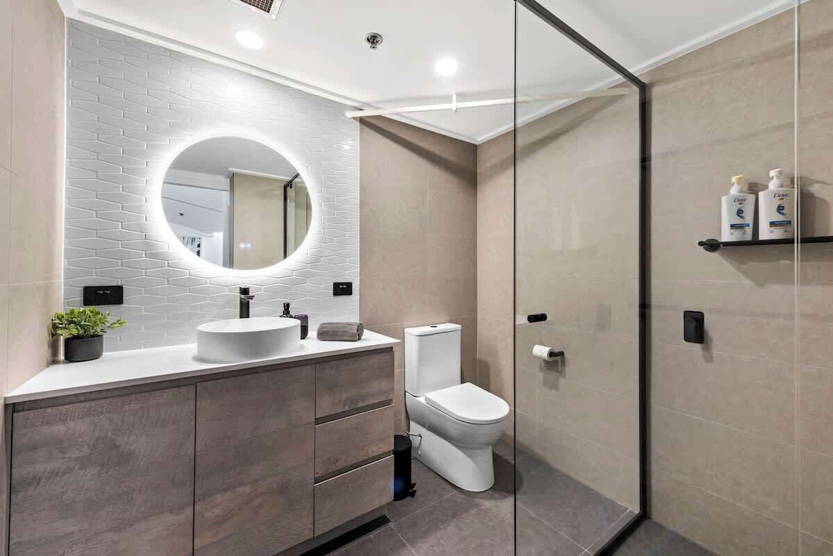 A modern bathroom with a white sink, a toilet, and a glass shower enclosure.