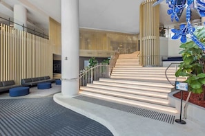 Eine moderne Lobby mit Treppe, Sitzbereichen und einer Wand aus vertikalen Holzelementen.