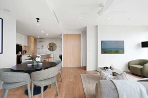 A modern living room with a dining area, a sofa, and a painting on the wall. - The Story Suite! 2bed/2bath/2car/pool/views ~ CBD (Brisbane)