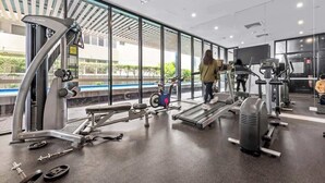 A gym with cardio machines, weightlifting equipment, and a large window offering a view of the outdoors. - South Bank Sleek! ~ 1bed/1bath/1car/balcony (Brisbane)
