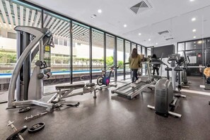 Ein Fitnessstudio mit Cardiogeräten, Gewichtstrainingsausrüstung und einem großen Fenster mit Blick ins Freie.