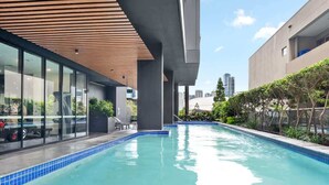 A swimming pool with a wooden ceiling, glass walls, and a city view. - South Bank Sleek! ~ 1bed/1bath/1car/balcony (Brisbane)
