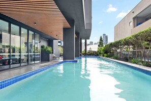 Ein Pool mit Holzboden, Glaswänden und Blick auf die Stadt.