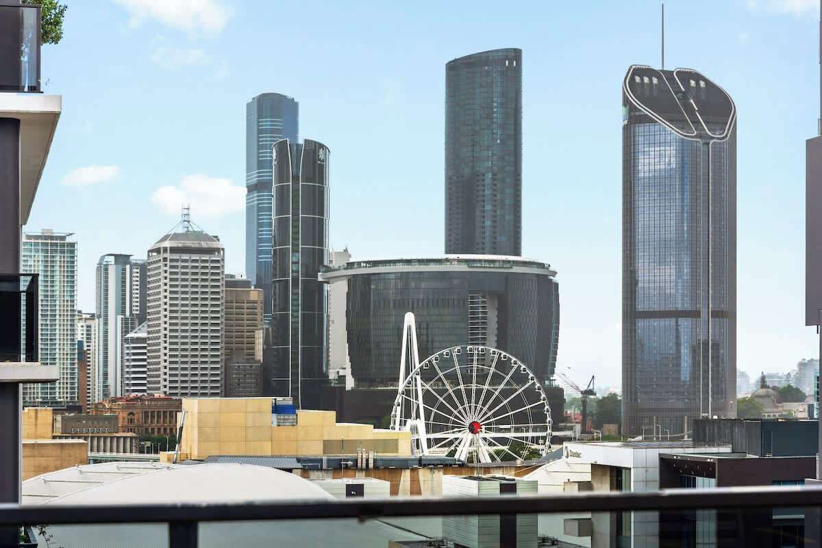 A cityscape with modern skyscrapers, a Ferris wheel, and a large building with a unique curved top.