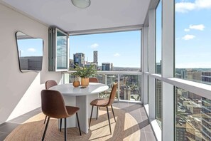 Ein moderner Essbereich mit einem runden Tisch, Stühlen und Blick auf die Stadt durch große Fenster.