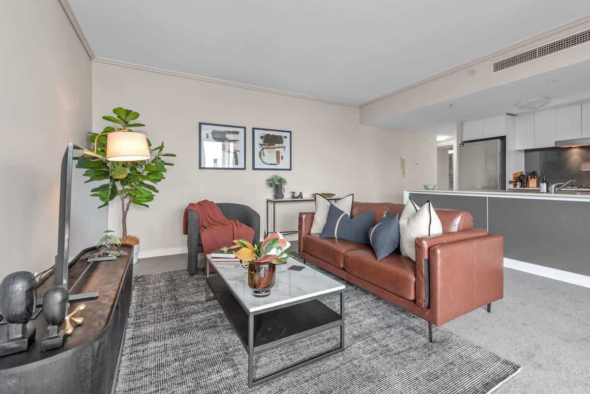 A modern living room with a sofa, coffee table, and a plant.