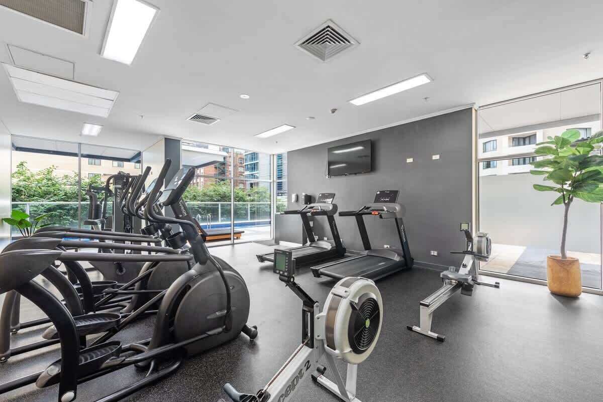 Une salle de sport équipée de vélos d’appartement, de tapis de course et d’un appareil d’aviron.