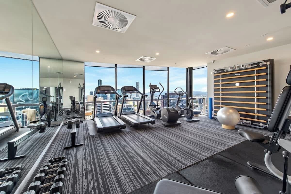 Un gimnasio moderno con cintas de correr, elípticas y pesas libres.