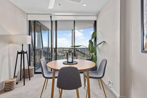 A modern room with a round table, two chairs, a floor lamp, and a large window with a view of the city. - Top Floor! 2bed/2bath/1car/pool ~ Views ~ CBD (Brisbane)