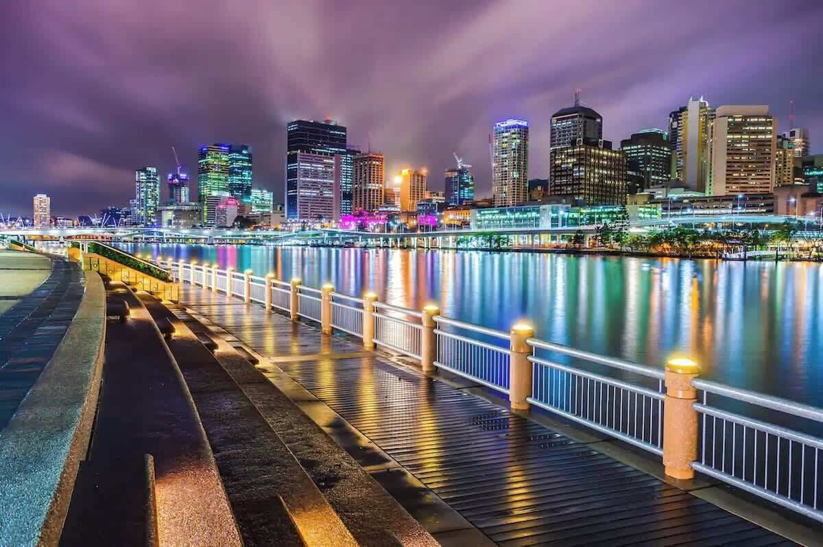 A waterfront cityscape with illuminated buildings at night.