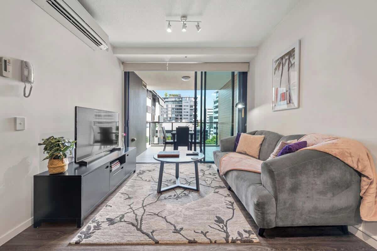 A modern living room with a sofa, TV, and a small table.