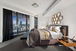 A modern hotel room with a large bed, a desk, a chair, a view of the city, and a large window with curtains. - Skyhigh Executive! ~ 2bed/2bath/1car/views ~ CBD (Brisbane)