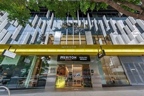A hotel entrance with a modern glass facade, a visible elevator, and a sign for Meriton Suites on Herschel Street, Brisbane. - Skyhigh Executive! ~ 2bed/2bath/1car/views ~ CBD (Brisbane)