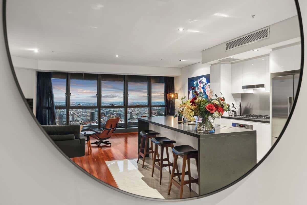 Une cuisine moderne avec vue sur la ville, un coin repas avec un canapé et des fauteuils, et un bar avec des tabourets.