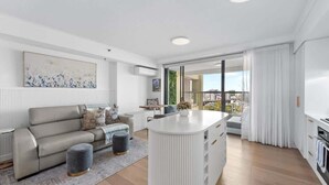 Een moderne woonkamer met een bank, een poef en een wit eiland met lades.