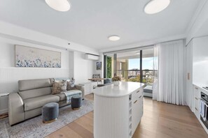 Ein modernes Wohnzimmer mit Sofa, Hocker und einer weißen Insel mit Schubladen.